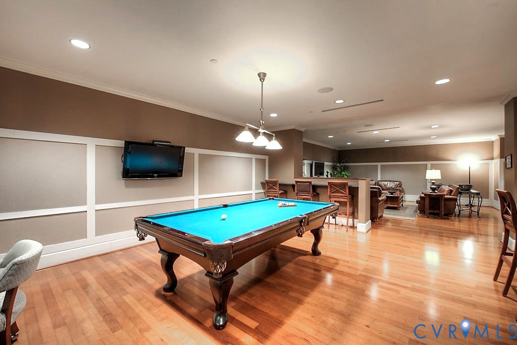 Wood-finish flooring, wainscoting paneling, recessed lighting, and a built-in bar counter