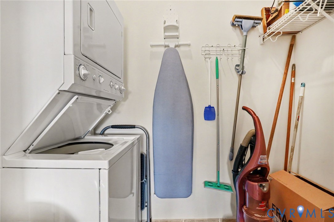 Dedicated laundry area featuring a white stacked washer and dryer unit and built-in wire wall shelving