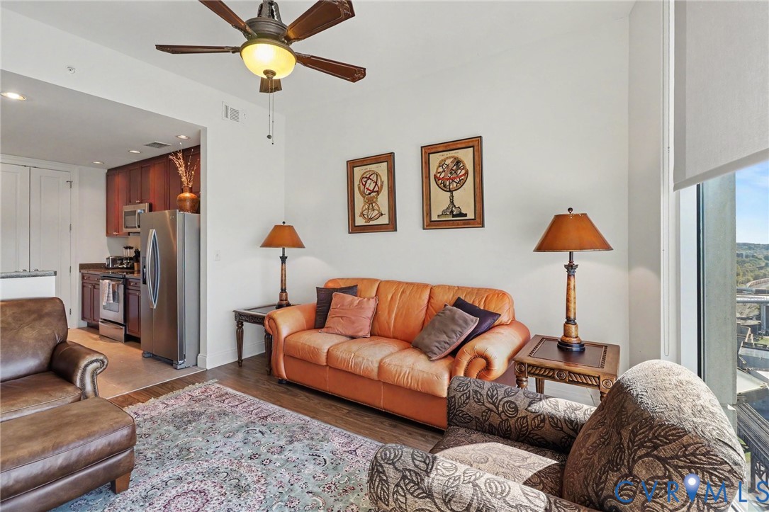 Open-concept living space with wood-finish flooring, ceiling fan, and floor-to-ceiling windows