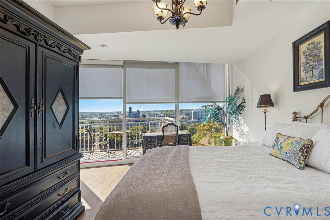 Floor-to-ceiling windows, wood-finish flooring, recessed lighting, ornate metal chandelier, and attached balcony
