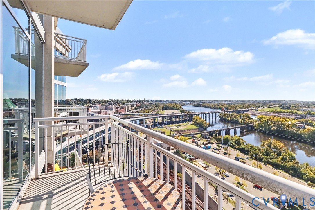 Private balcony with white metal railing, floor-to-ceiling glass exterior wall, and metal facade detailing