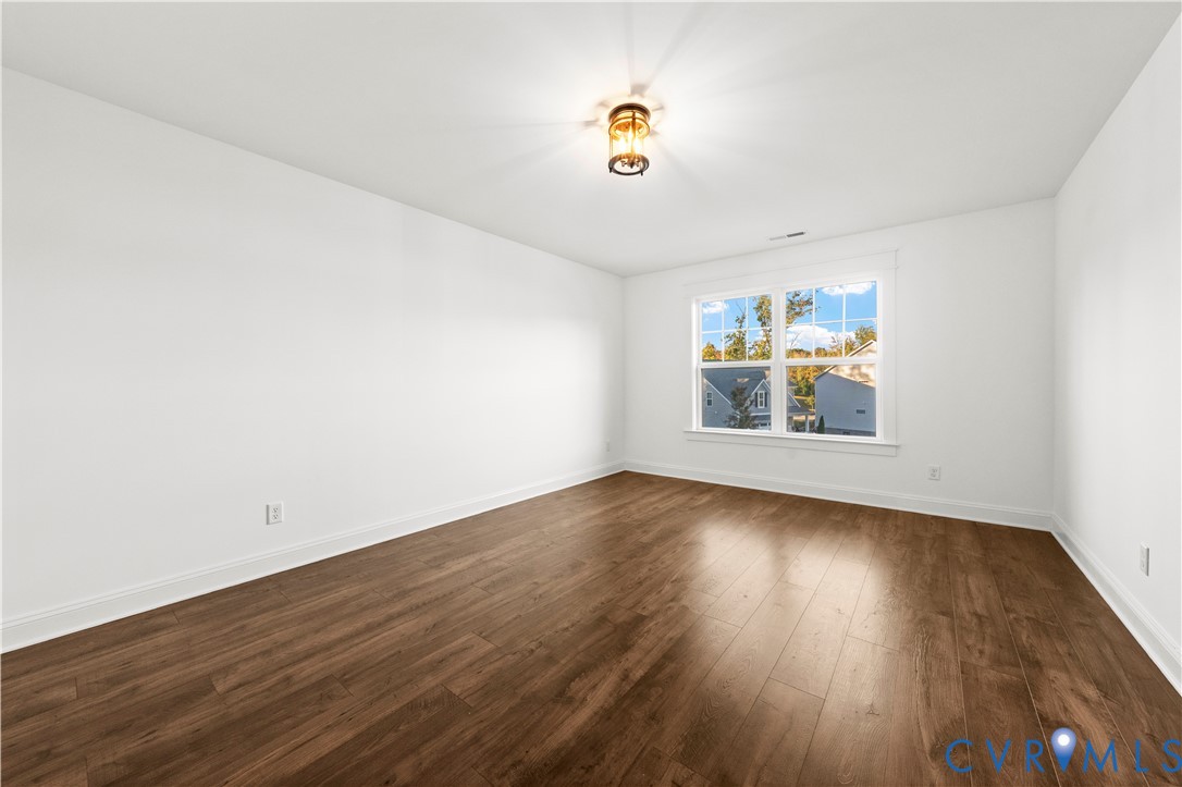 Room featuring wood-finish flooring, a multi-pane window, and a central flush-mount light fixture
