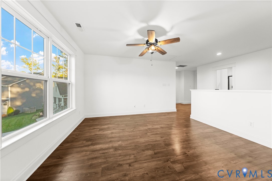 Wood-finish flooring, multi-pane windows, and a ceiling fan with integrated lighting