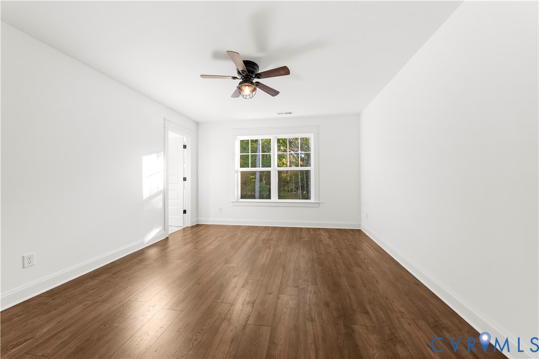 Room featuring wood-finish flooring, a multi-pane window, and a ceiling fan with integrated lighting