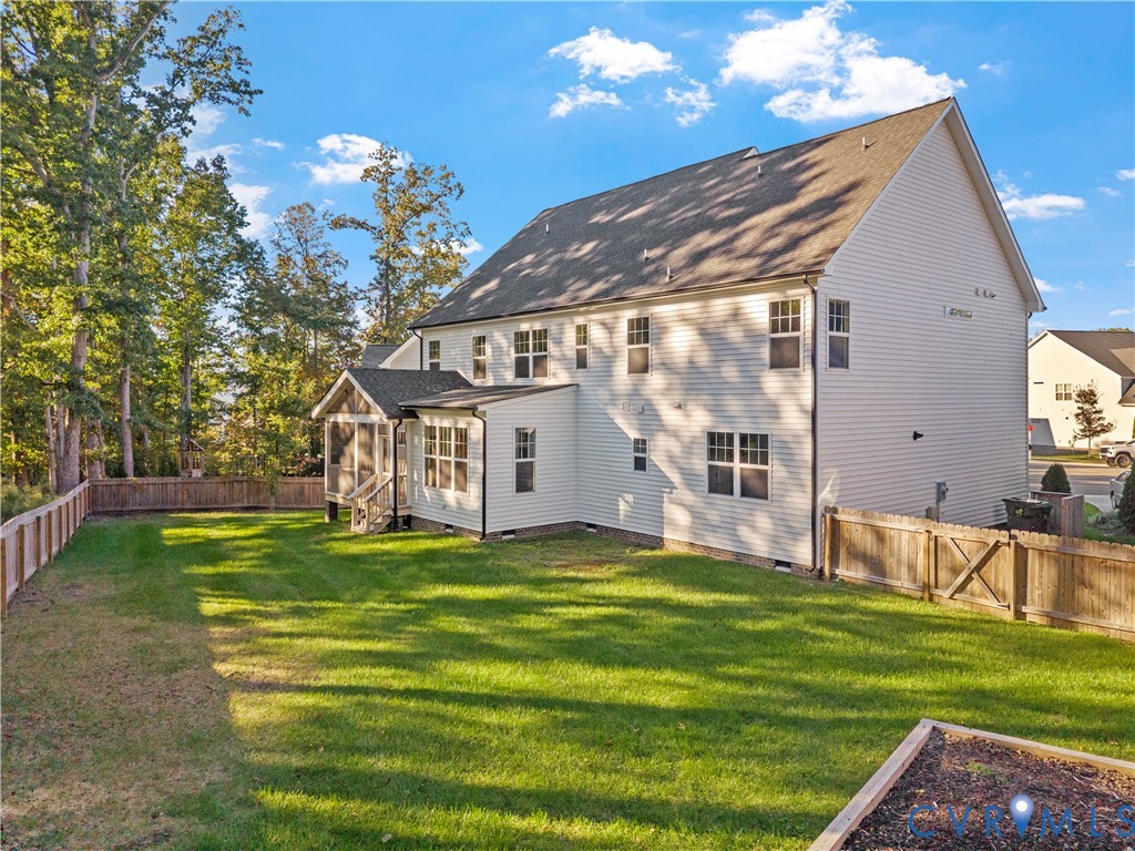 Rear exterior featuring vinyl siding, screened-in porch, fully fenced backyard, and raised garden bed