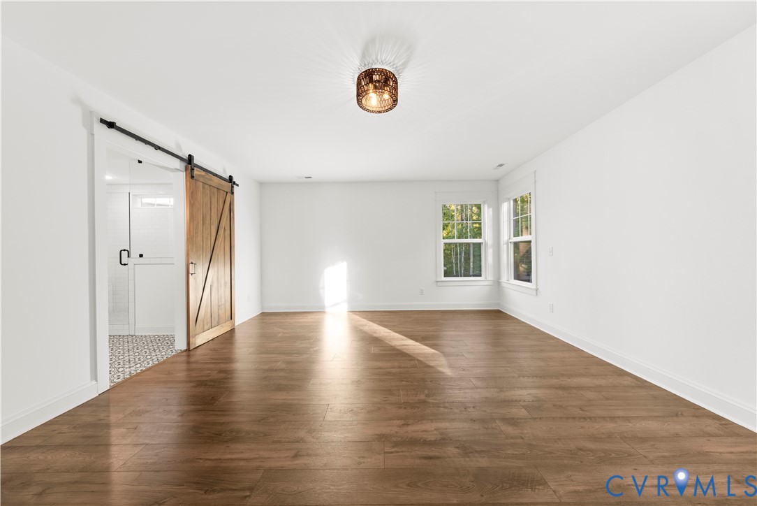 Interior space featuring wood-finish flooring, a decorative metal drum light fixture, and a sliding wood-tone barn door with matte black hardware