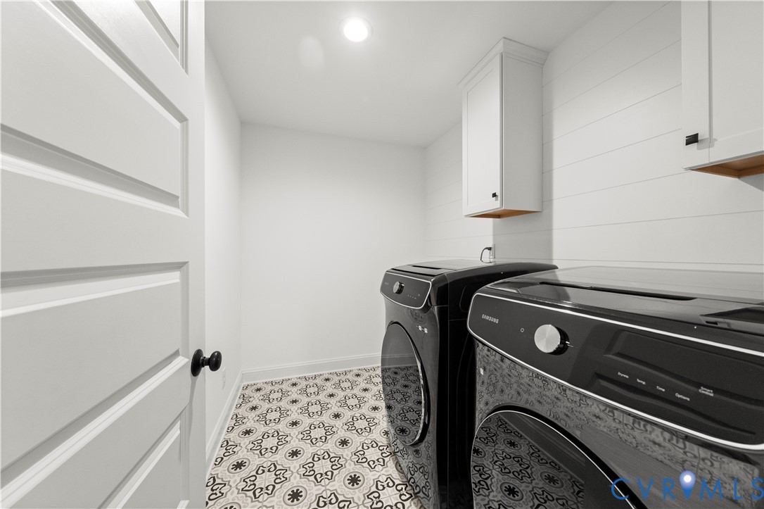 Laundry space featuring patterned tile flooring, white horizontal shiplap wall detailing, and shaker-style upper cabinetry