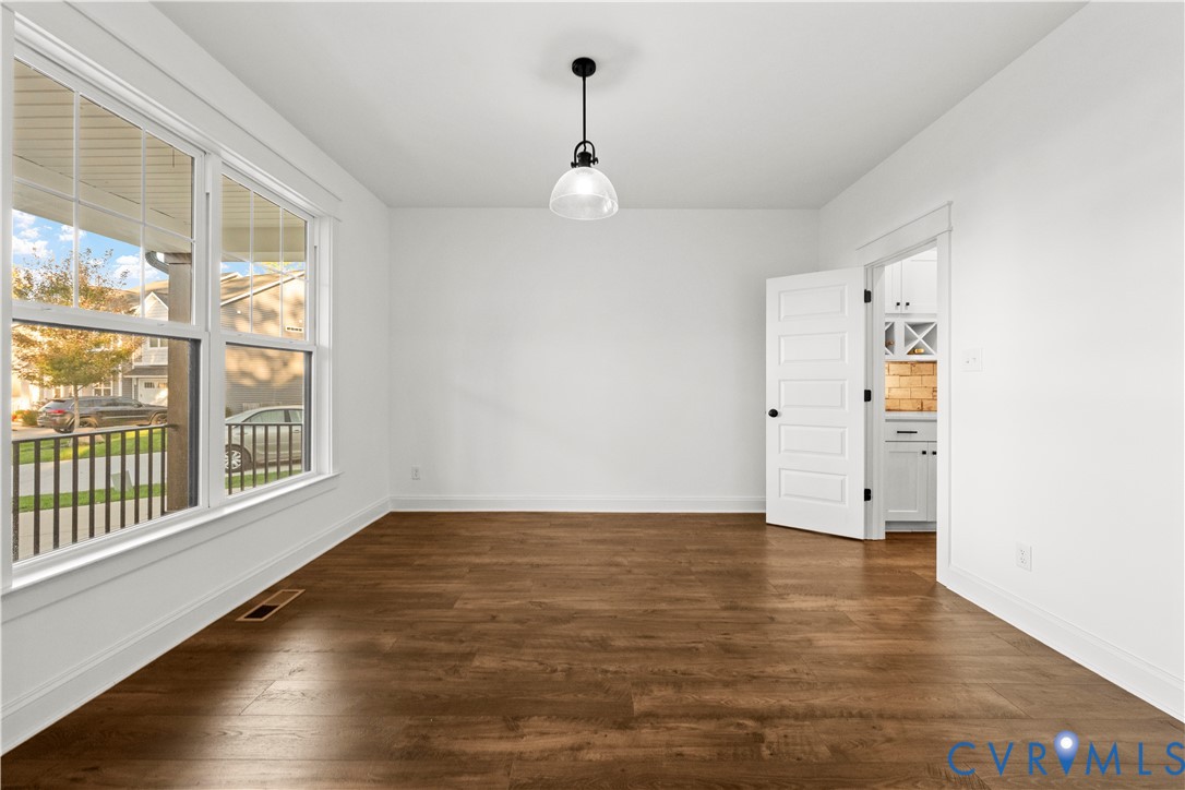 Wood-finish flooring, large multi-pane windows, five-panel interior door, and a single-pendant light fixture