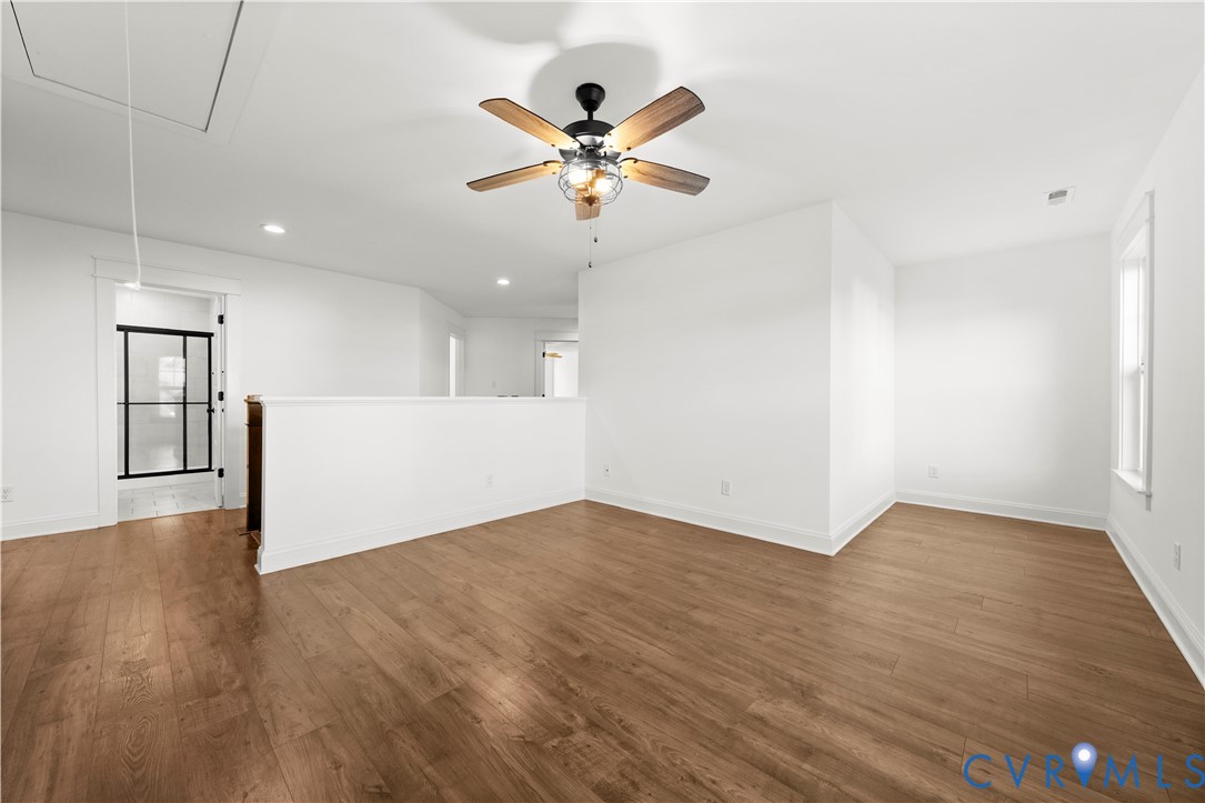 Open-concept interior featuring wood-finish flooring, a ceiling fan with integrated lighting, recessed lighting, and a half-wall partition