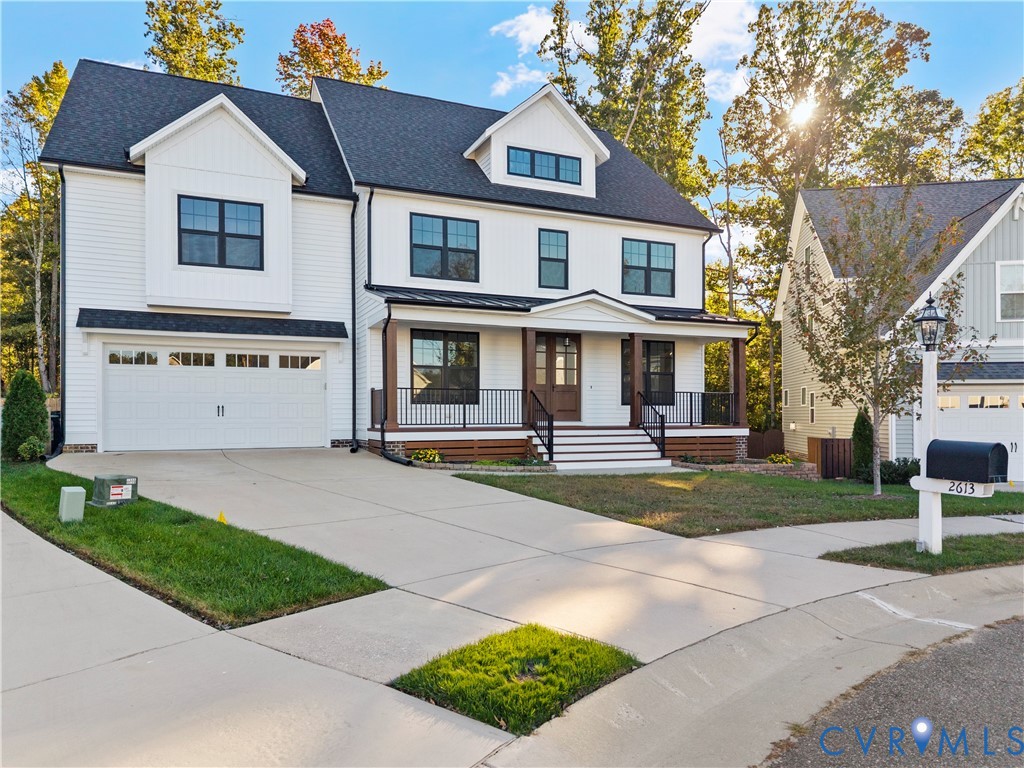 Multi-level exterior featuring white siding, a metal-accented front porch with dark railings, a steeply pitched roof, and an attached two-car garage
