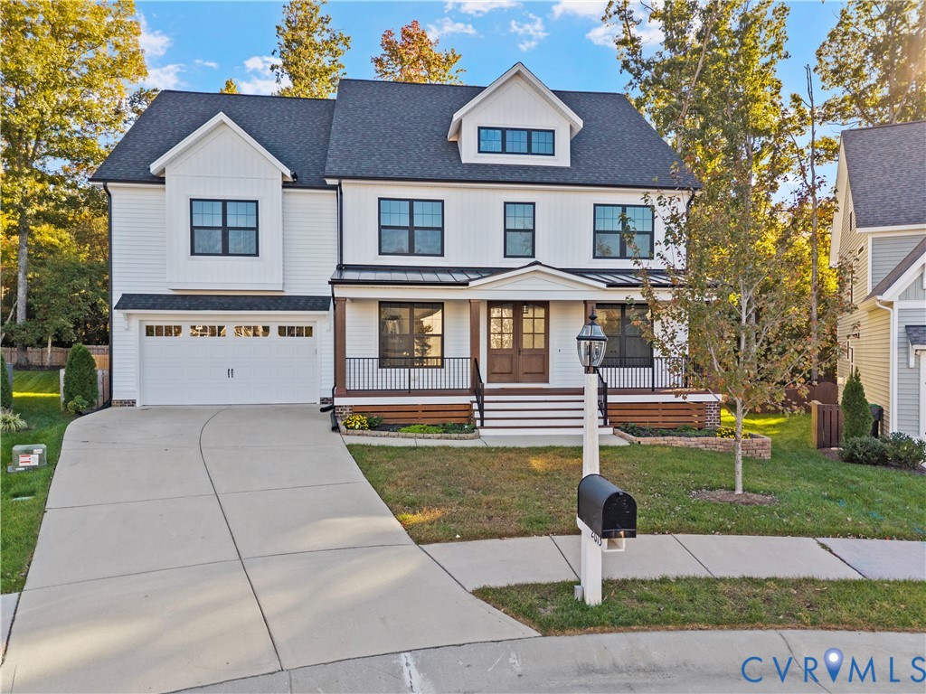 Two-story residence featuring a white vertical and horizontal siding exterior, dual-gabled roofline, metal porch awning, iron railings, and a concrete driveway