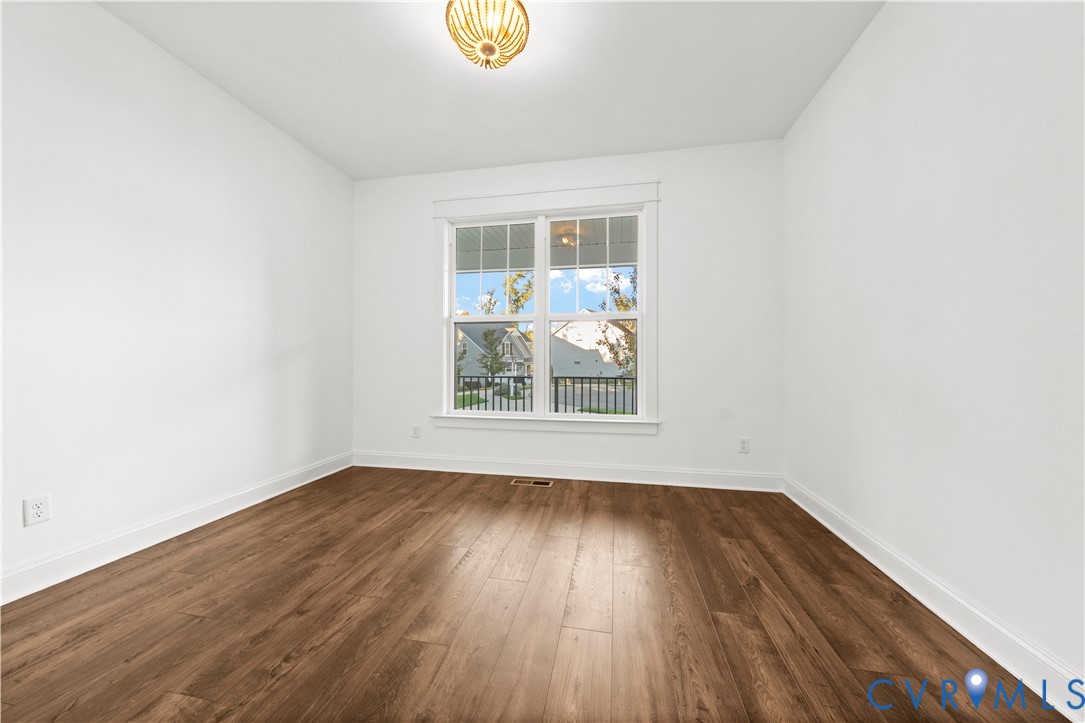 Room featuring wood-finish flooring, a multi-pane window with custom trim, and a globe-style flush-mount light fixture