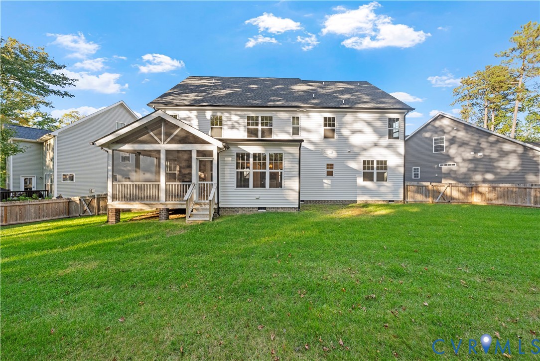 Rear exterior featuring light-toned horizontal siding, a covered screened-in porch with wood-style railings, a multi-paneled roof structure, and a fenced backyard with a manicured lawn
