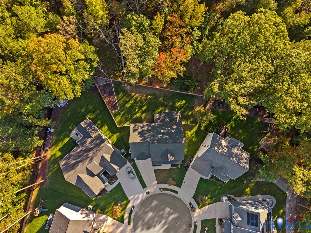 Aerial perspective of residential properties located on a cul-de-sac, featuring concrete driveways, shingled roofing, and established perimeter foliage