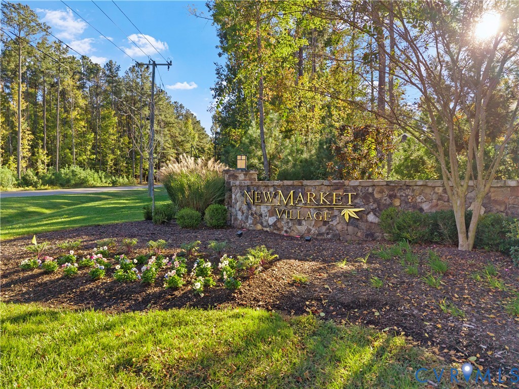 Stone monument signage featuring dimensional gold-toned lettering, set within a landscaped community entrance with mature trees and groomed shrubbery
