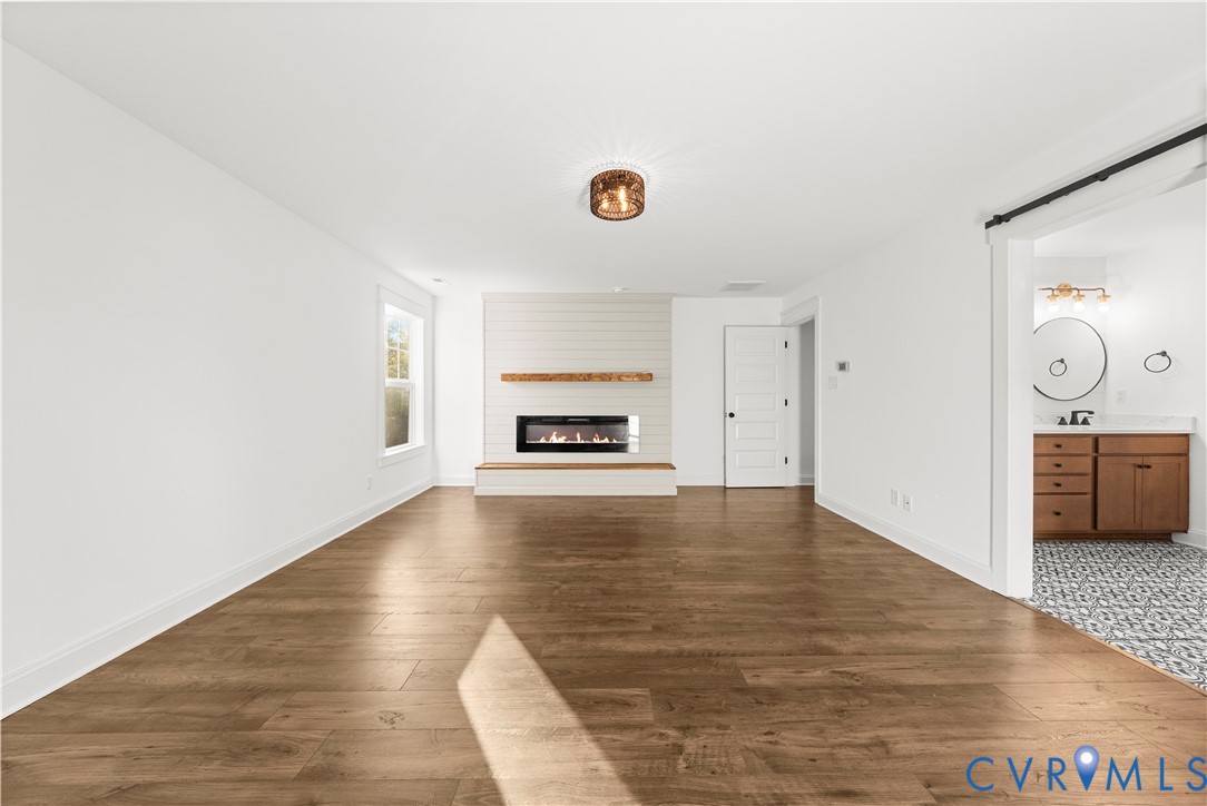 Wood-finish flooring, horizontal shiplap accent wall, built-in linear fireplace with natural wood mantel, and custom farmhouse-style door hardware