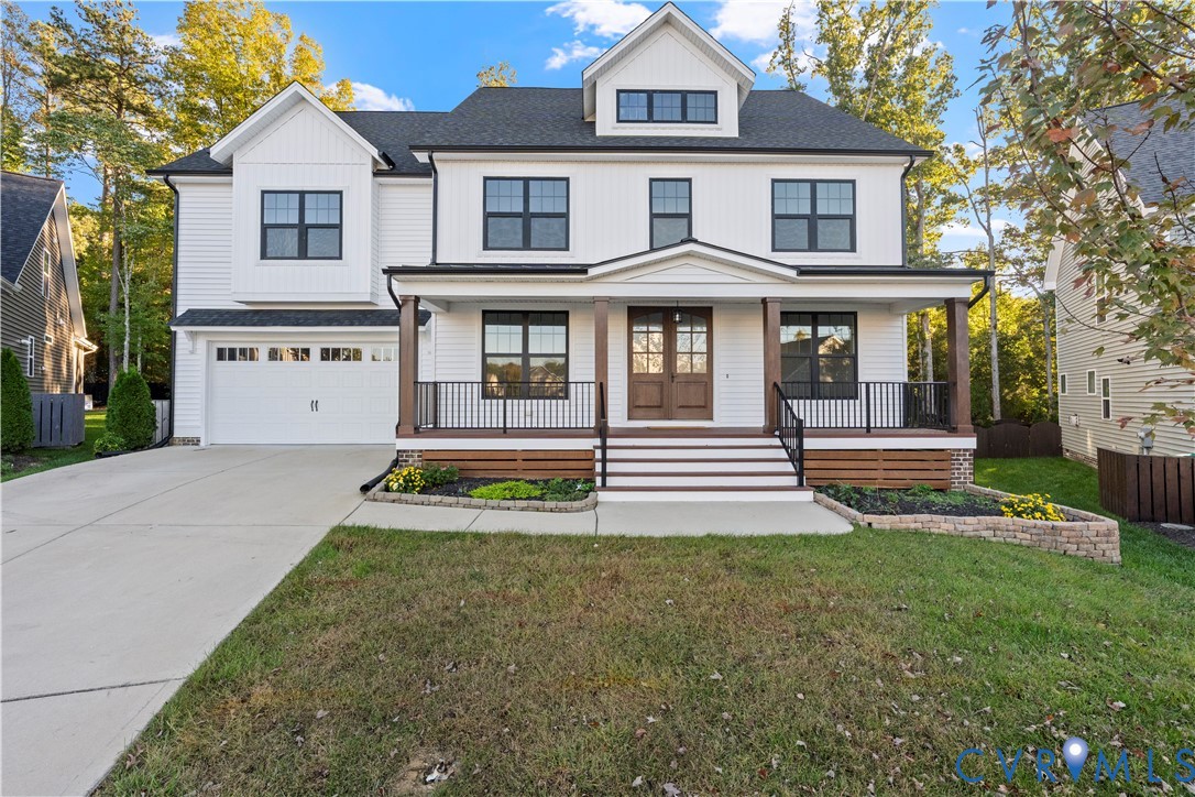 Two-story exterior featuring white horizontal siding, dark-framed windows, a covered front porch with timber-finished columns, a double-door entrance, and an attached two-car garage