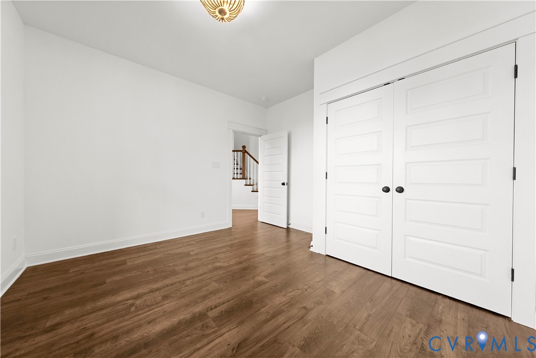 Room featuring wood-finish flooring, white five-panel interior doors, and a decorative flush-mount ceiling fixture