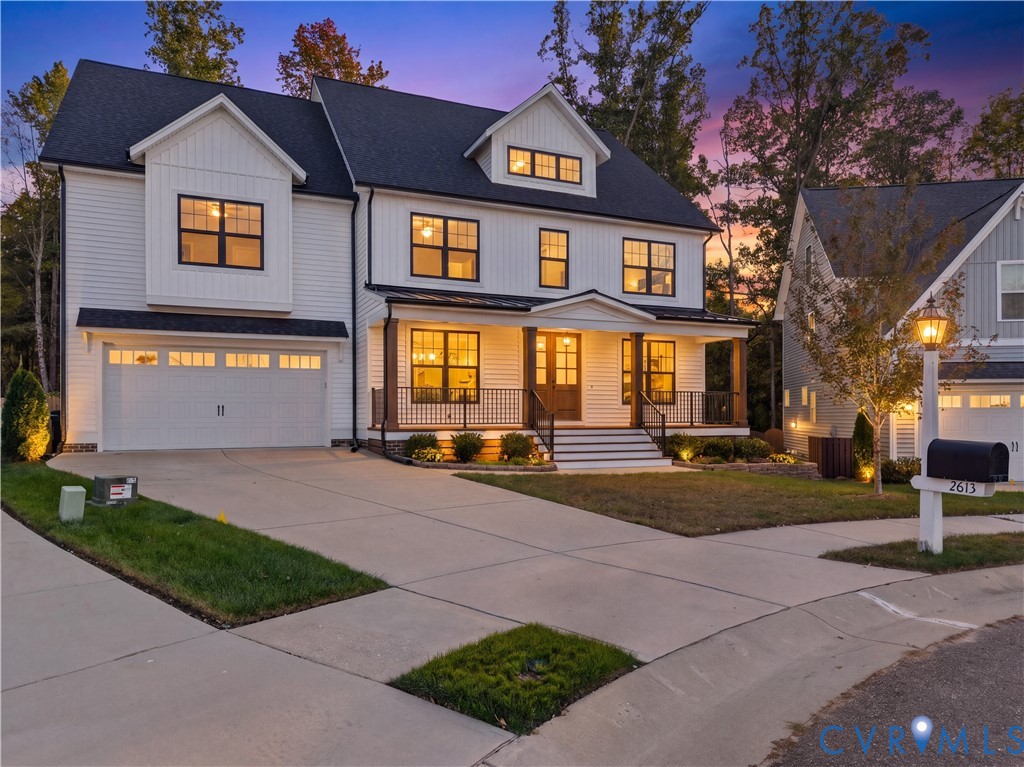 Two-story residence featuring a white vertical-board exterior, a covered front porch with metal railing, a shingled roof with a front-facing gable, and an attached two-car garage