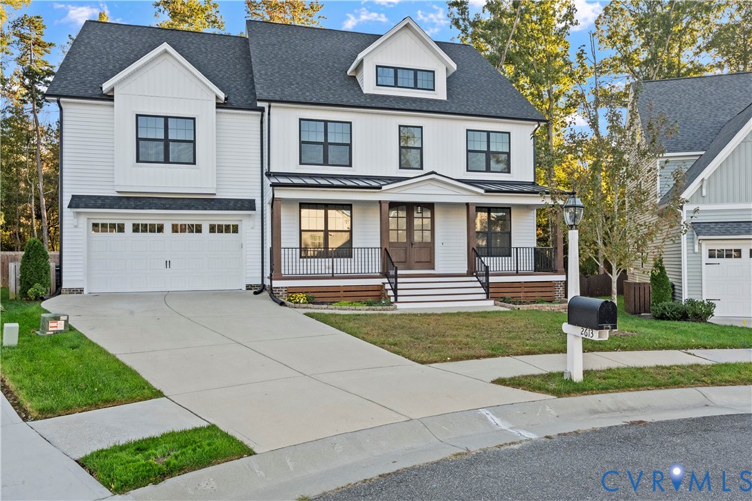 Two-story residence featuring white horizontal siding, a covered front porch with metal roofing, dark-stained double front entry doors, and a double-car garage