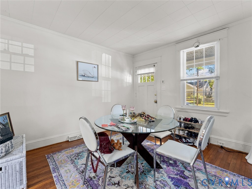 Room featuring wood-finish flooring, paneled ceiling, and a multi-pane window with exterior molding