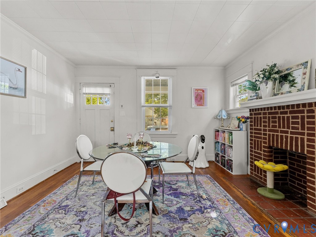 Exposed brick fireplace with a custom mantel, wood-finish flooring, and multi-pane windows