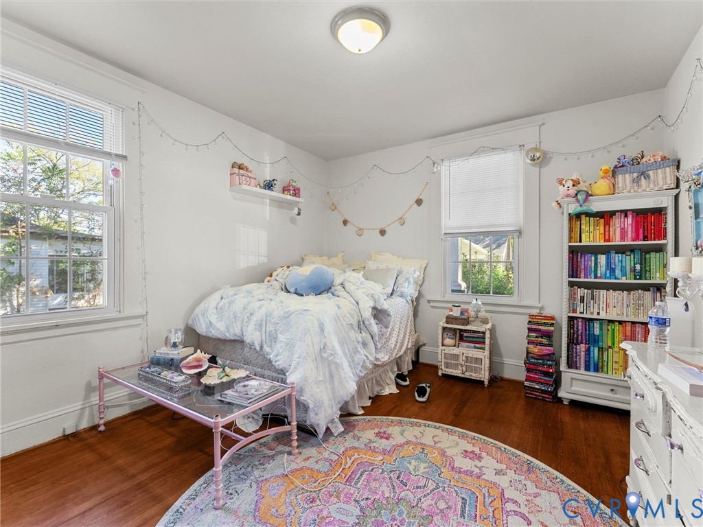 Room featuring wood-finish flooring, dual windows with grid detailing, and a wall-mounted floating shelf