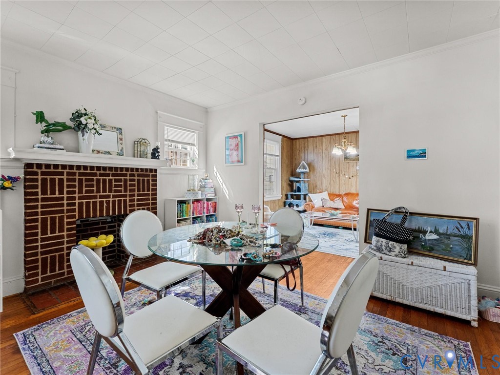 Interior space featuring a brick fireplace with a decorative mantel, wood-finish flooring, and a paneled ceiling