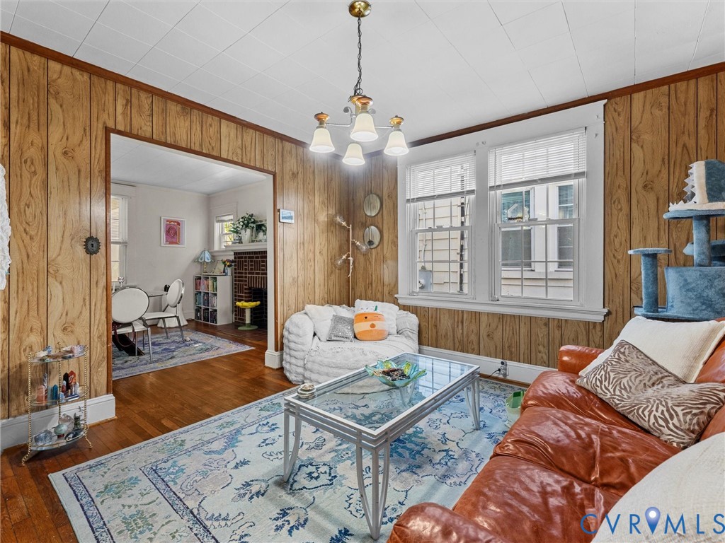 Wood-paneled walls, hardwood flooring, multi-pane windows, and a multi-arm pendant light fixture