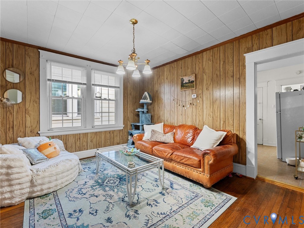 Wood-paneled walls, hardwood flooring, multi-pane windows, and a multi-arm chandelier