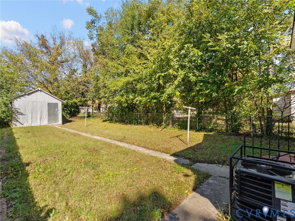 Backyard featuring a detached metal storage shed, chain-link perimeter fencing, and mature trees
