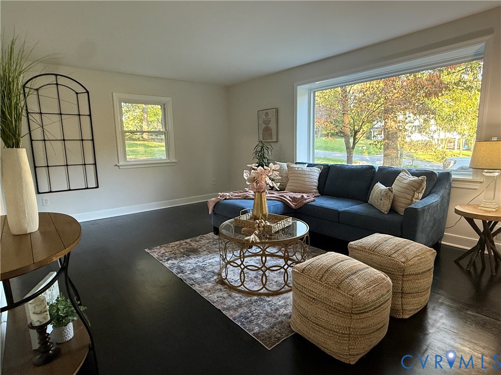 Living area featuring dark-stained wood-finish flooring, a large picture window, and neutral wall tones