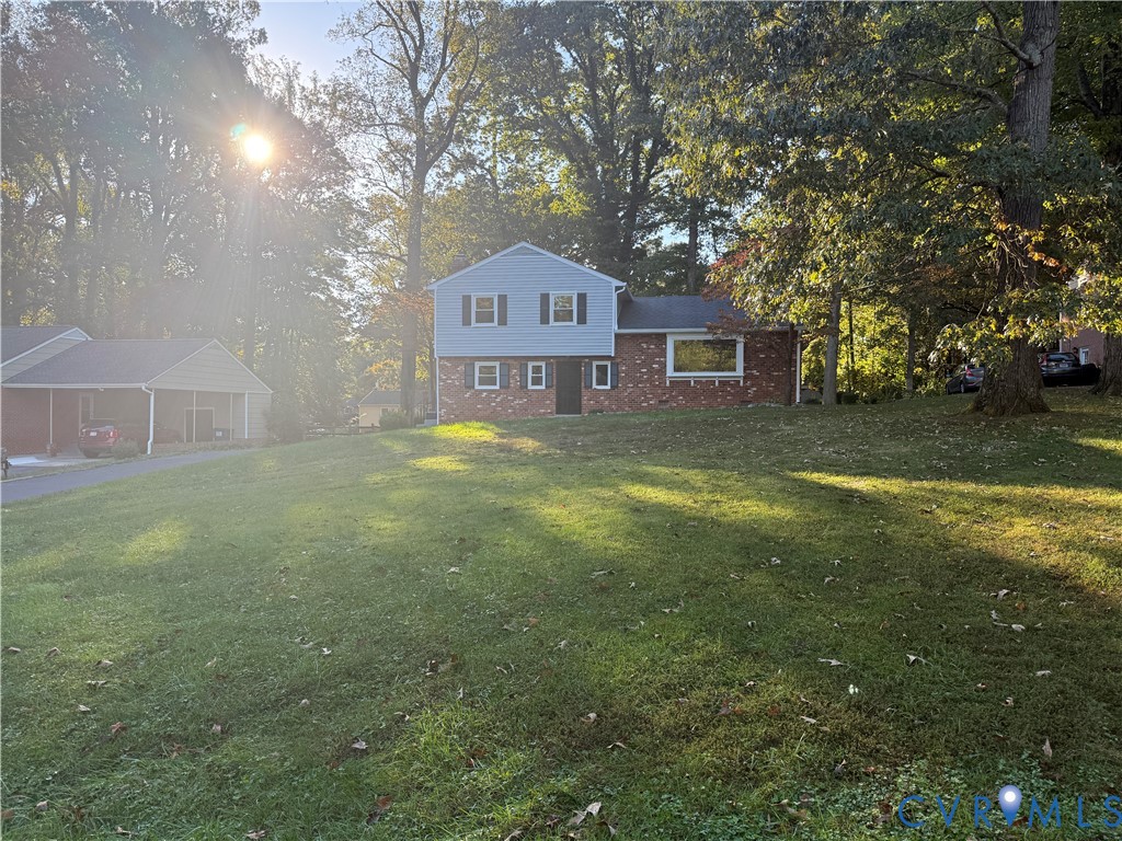 Two-story residence featuring a mixed brick and siding exterior, multi-pane windows, and a detached carport situated on a tree-lined lot