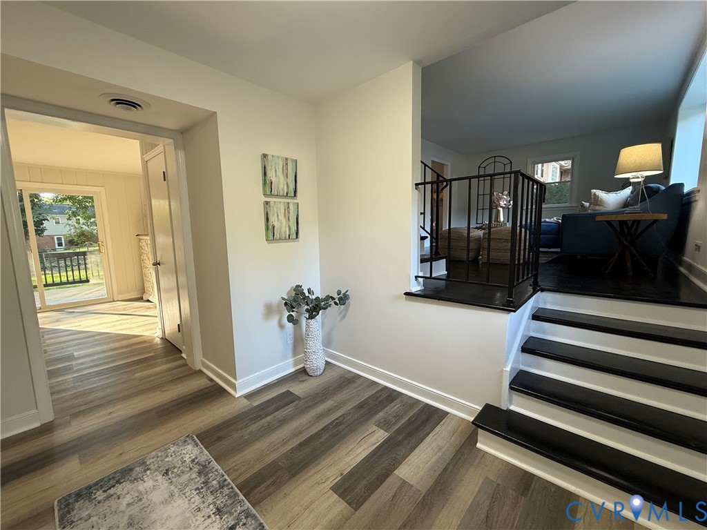 Interior featuring wood-finish flooring, a tiered floor plan with staircase, and wrought iron balustrade