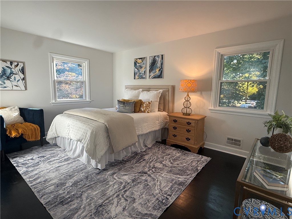 Spacious room featuring dark-stained wood-finish flooring, neutral wall tones, and two double-hung windows