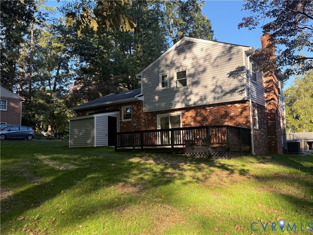 Two-story residence featuring a brick and horizontal siding exterior, attached wood deck, and external brick chimney