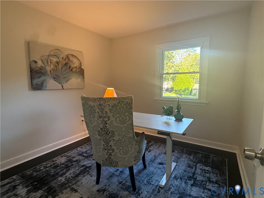 Neutral interior space featuring wood-finish flooring, crisp neutral wall paint, and a double-hung window with decorative casing
