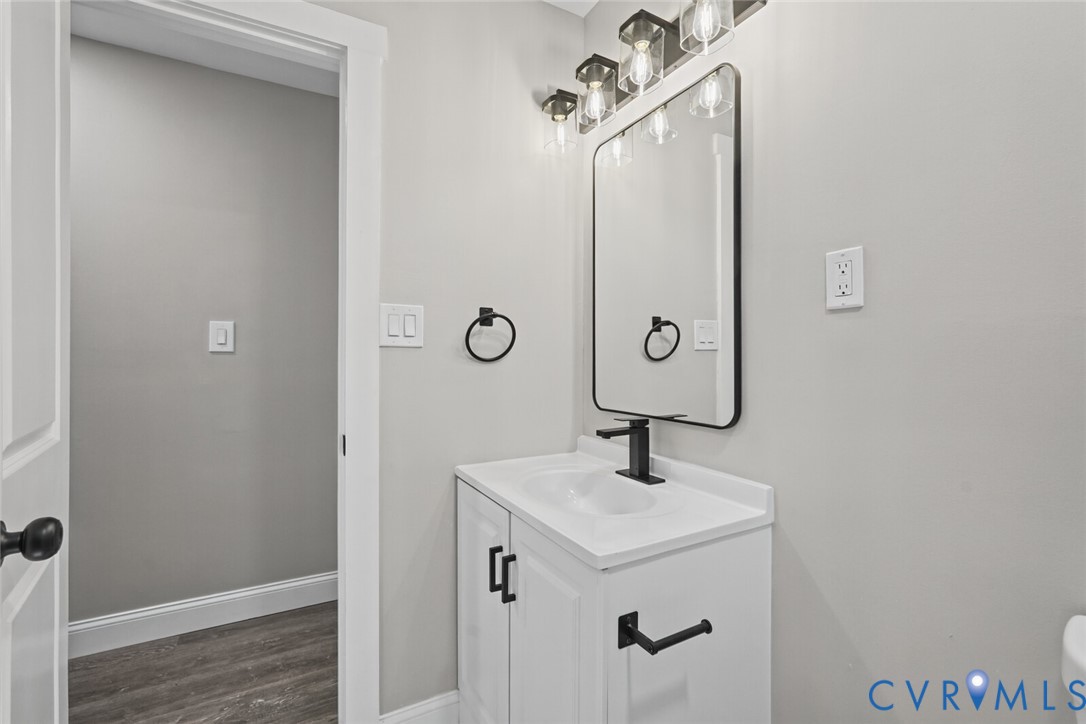 White vanity cabinet with an integrated sink, rectangular mirror with a black frame, matte black faucet, and coordinating black hardware