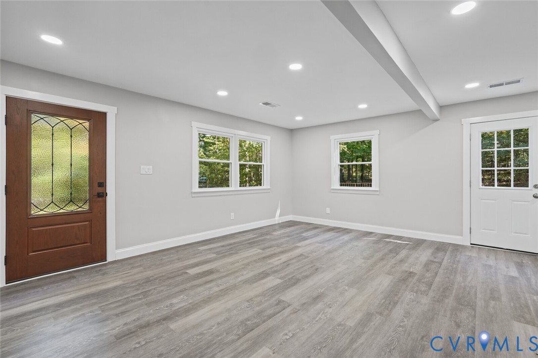 Interior space featuring wood-finish flooring, recessed lighting, a decorative glass-panel entry door, and a white multi-lite exterior door