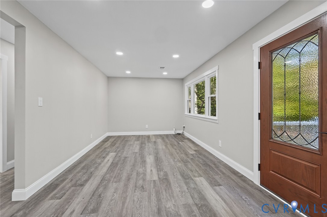 Interior space featuring wood-finish flooring, recessed lighting, neutral wall paint, and a wood entry door with glass paneling