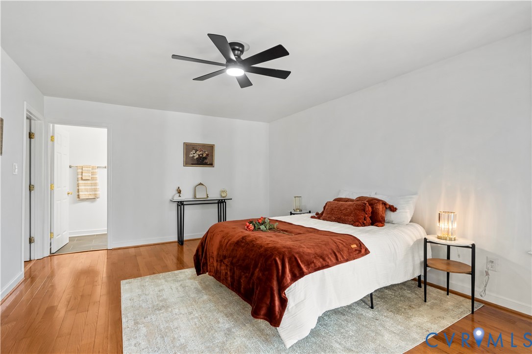 Wood-finish flooring, multi-blade ceiling fan with integrated lighting, and white interior doors