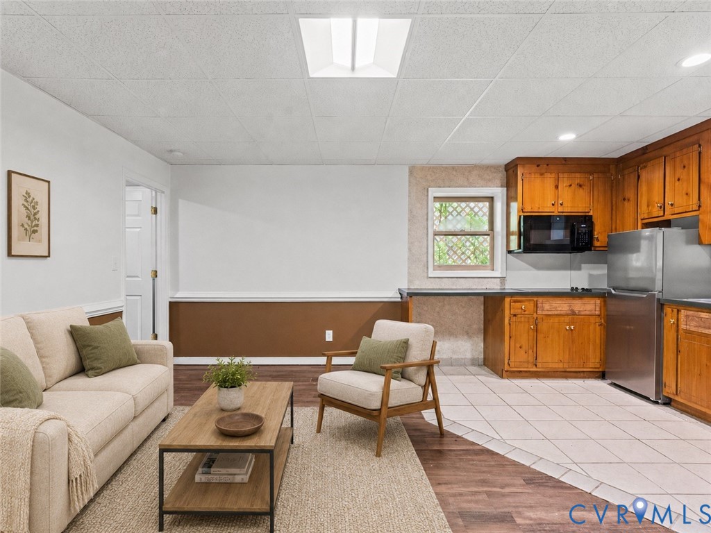 Kitchen area featuring wood cabinetry, stainless steel appliances, tile flooring, and integrated lighting