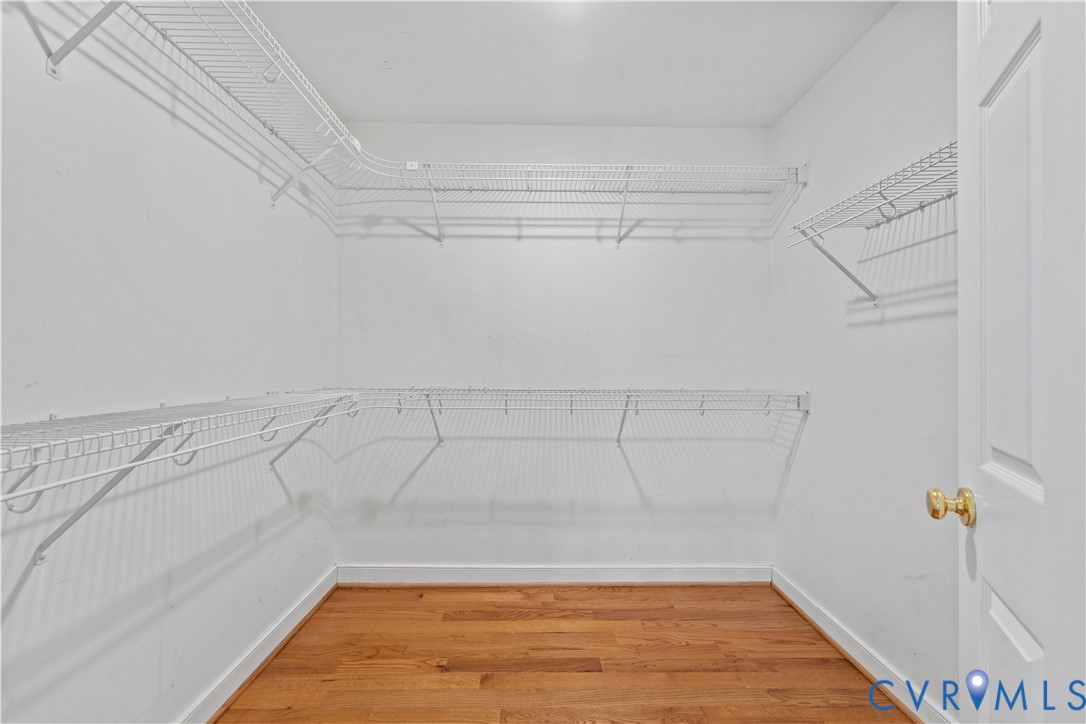 Storage area featuring multi-level white wire shelving and wood-finish flooring