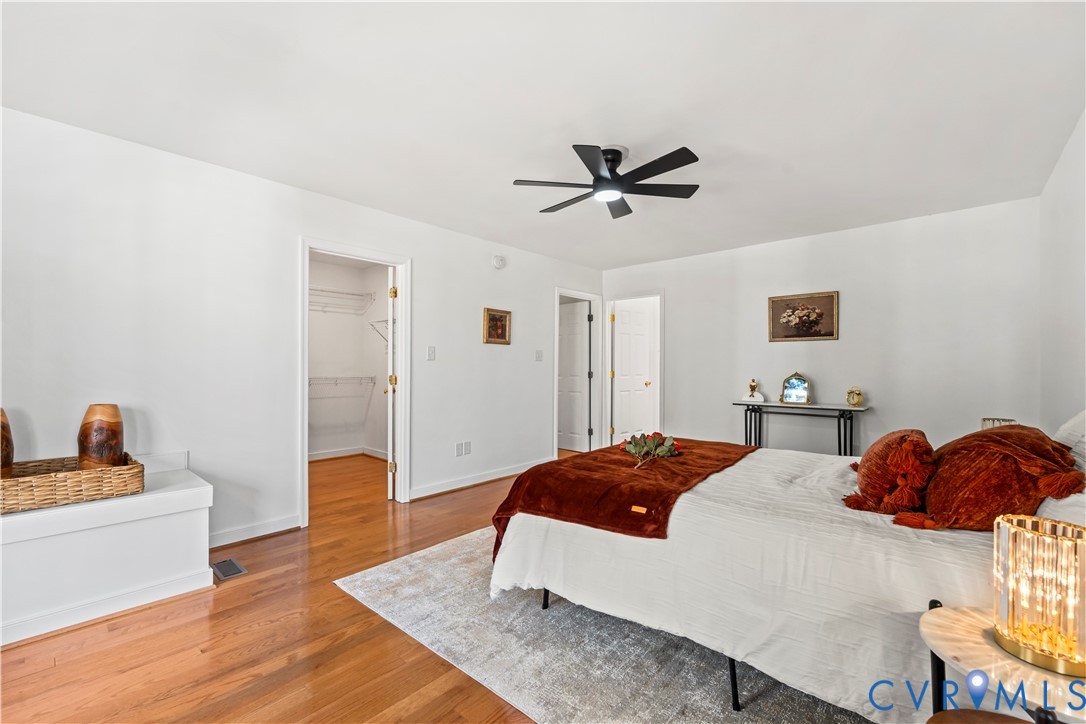 Wood-finish flooring, matte black ceiling fan, and walk-in closet featuring wire shelving
