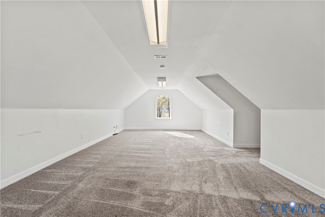 Finished space with arched window, neutral wall-to-wall carpeting, and dual flush-mount ceiling light fixtures