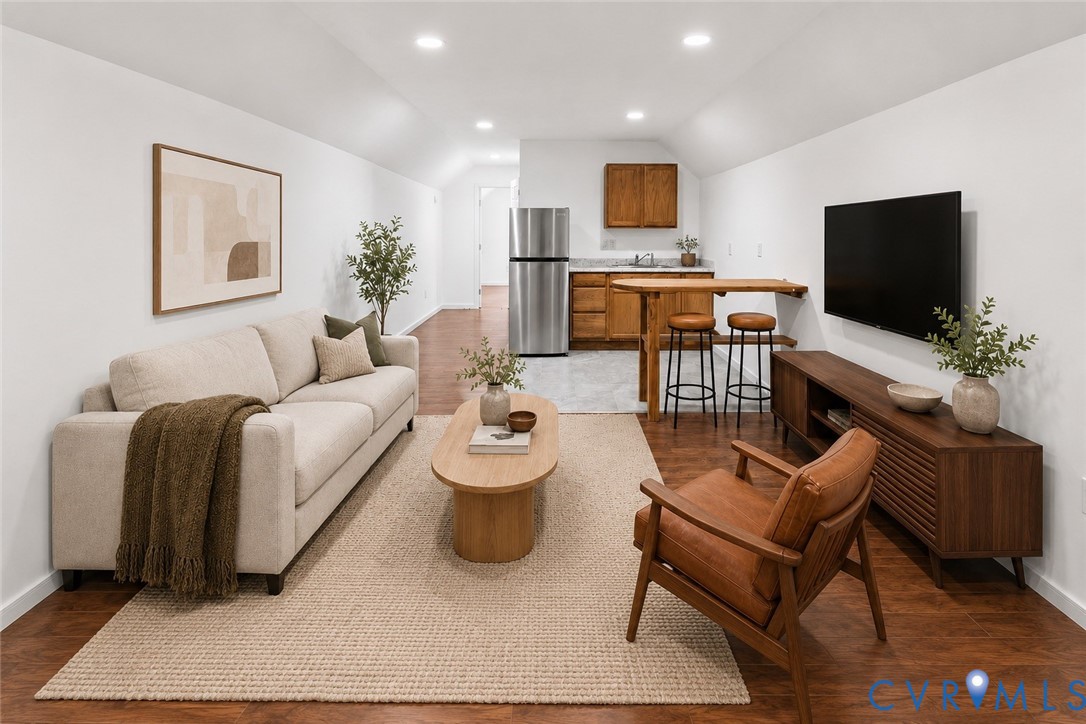 Finished interior space featuring wood-finish flooring, recessed lighting, and a kitchenette equipped with wood cabinetry and a stainless steel refrigerator