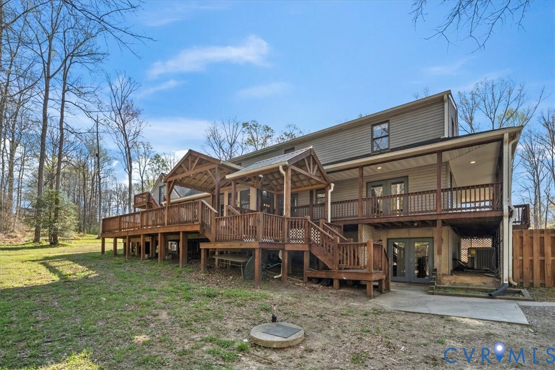 Multi-level wood deck featuring a covered timber-framed patio, decorative railings, and stairs