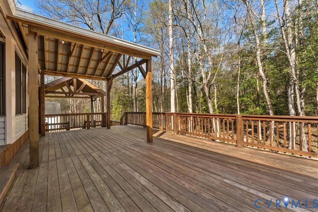 Expansive wood deck featuring a covered timber-framed porch, exposed rafters, and wooden balustrades