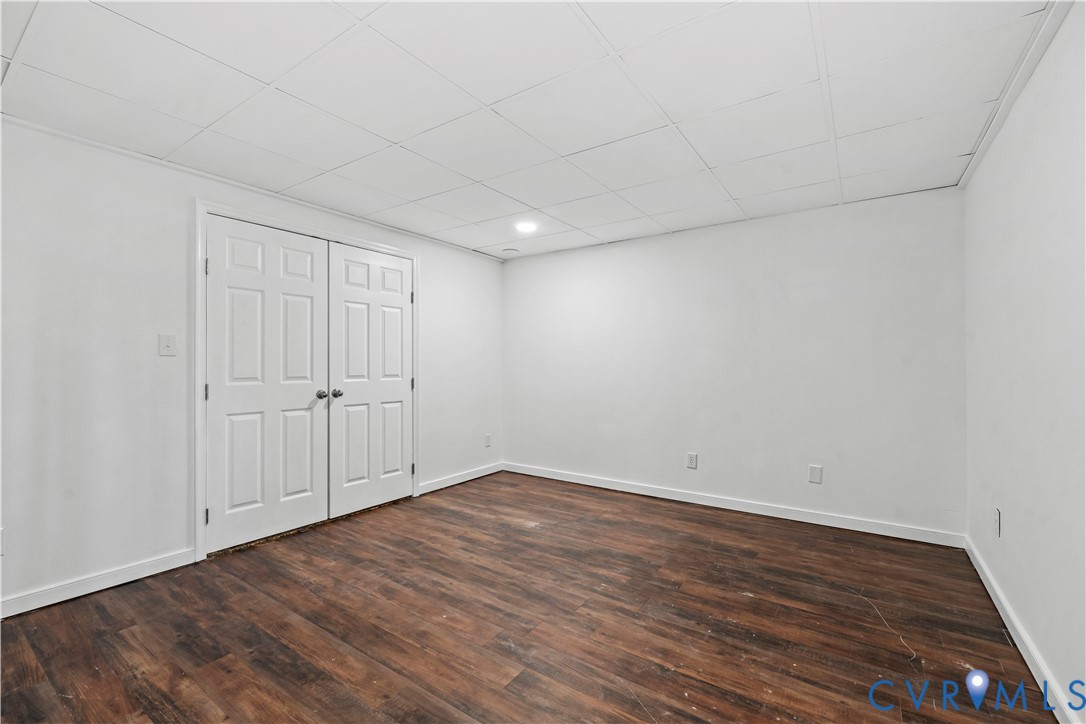 Interior space featuring wood-finish flooring, a suspended drop ceiling, recessed lighting, and double-panel doors