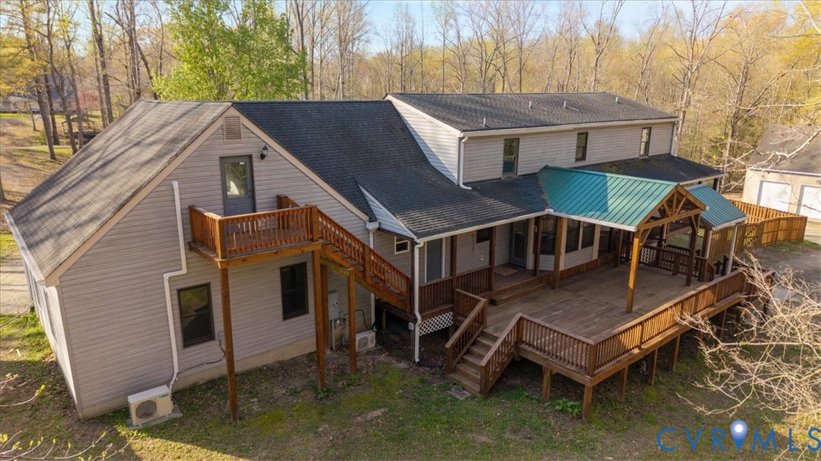 Exterior featuring light gray vinyl siding, multi-level wood deck, metal-roofed covered porch area, and elevated wood balcony with stairs